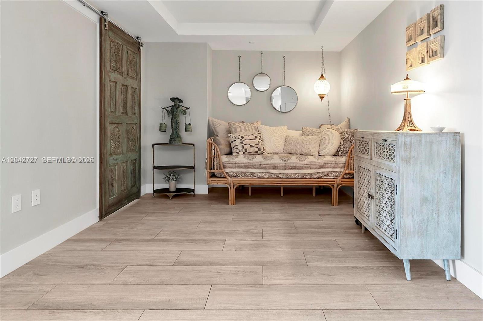 A room features a daybed, a wooden sliding door, and a decorative cabinet on wood-look flooring — 121 NE 34th St # 2502, Miami FL 33137, MIAMI, FL