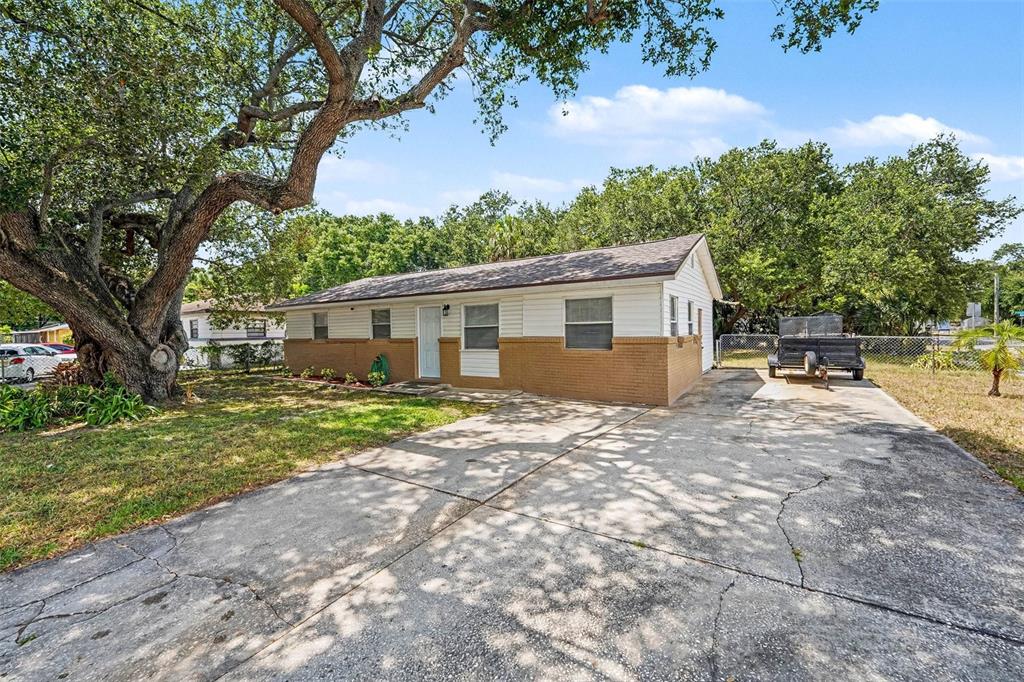 A single-story house with a brick and white siding exterior sits behind a concrete driveway — 7924 BAHIA AVENUE, TAMPA, FL