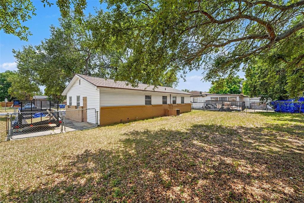 A side view of a single-story house with white siding and a brown brick base — 7924 BAHIA AVENUE, TAMPA, FL