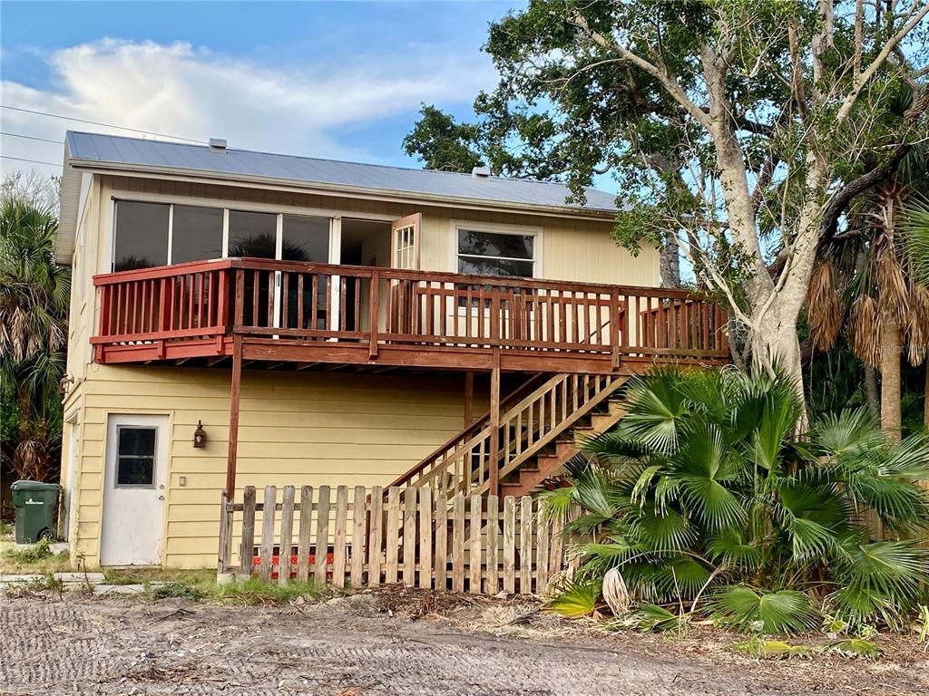 A two-story house with yellow siding, a wooden deck, and an exterior staircase — 7820 MIDNIGHT PASS, SARASOTA, FL