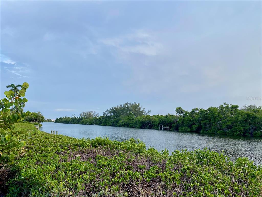 A view of a narrow waterway lined with dense green mangroves under a cloudy sky — 7820 MIDNIGHT PASS, SARASOTA, FL