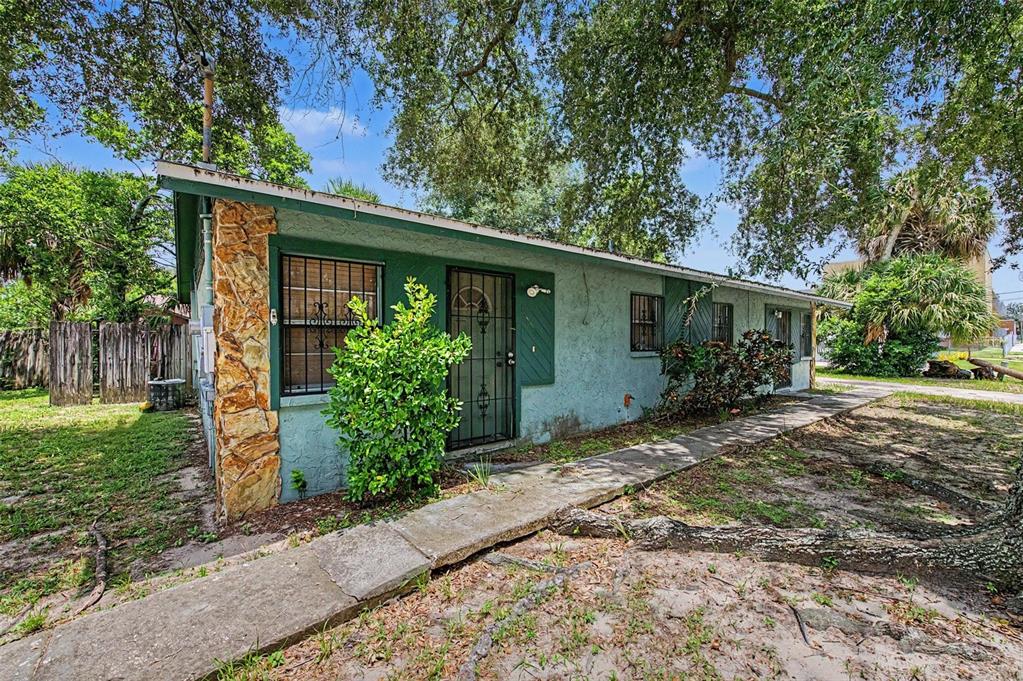 A single-story house with a stone corner, green stucco walls, and a concrete walkway — 8605 N 12TH STREET, TAMPA, FL