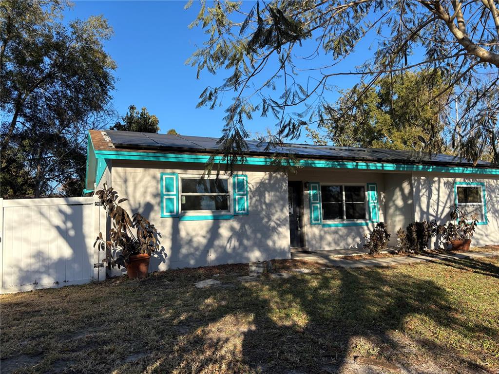 A single-story house with a light-colored block exterior, teal trim, and a front lawn — 710 EAST COURT, LONGWOOD, FL