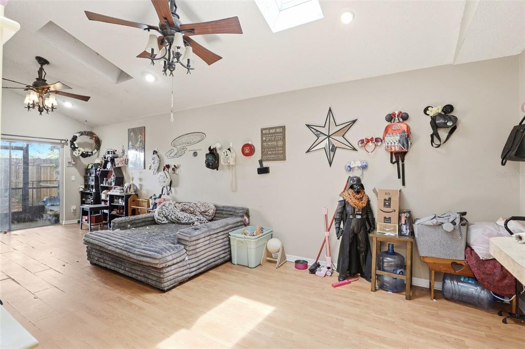 A living room with light wood-look flooring, two ceiling fans, and various Star Wars decorations — 1281 CROSSFIELD DRIVE, APOPKA, FL