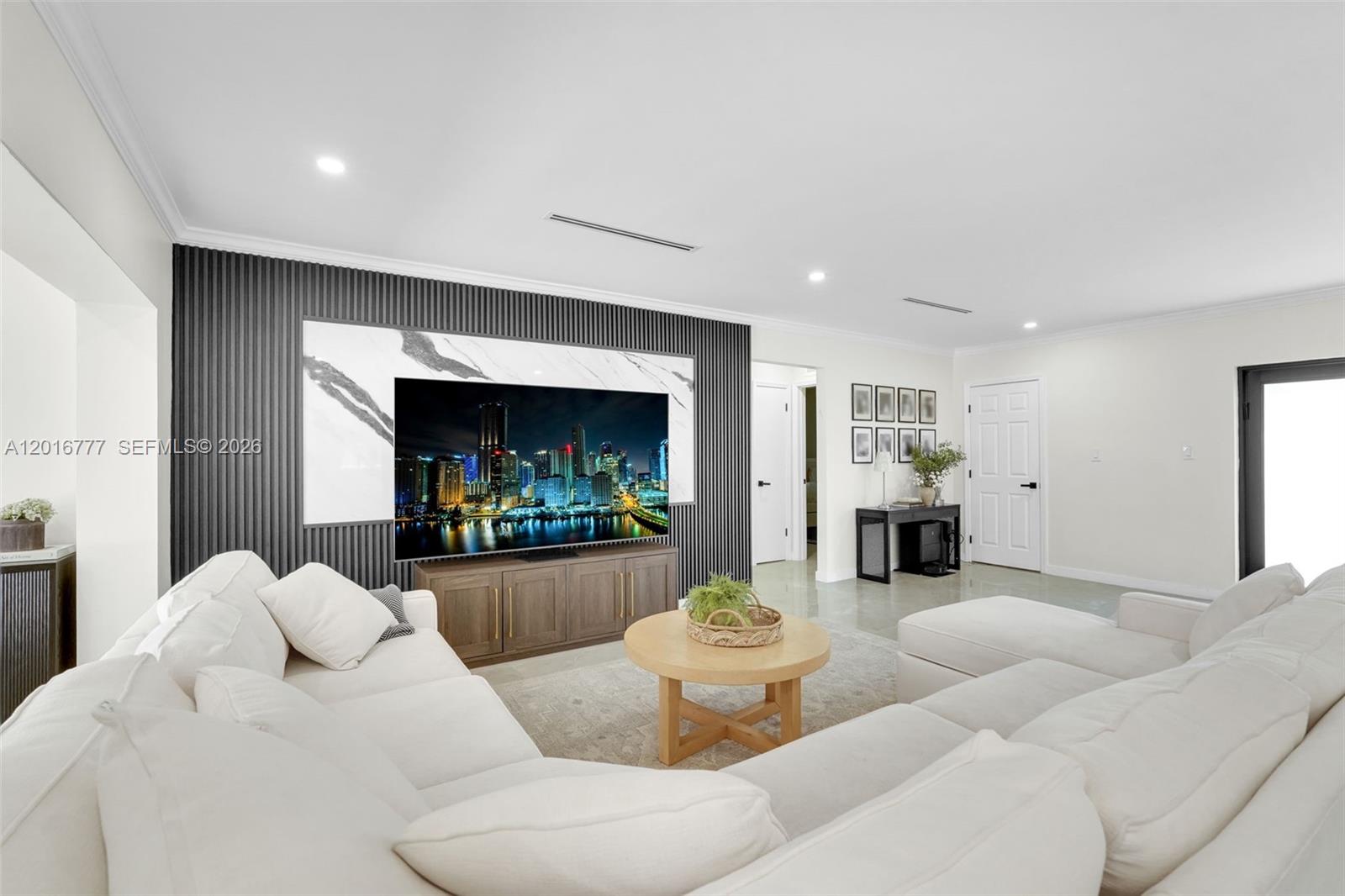 A living room features a large television mounted on a dark slatted accent wall — 3411 Thomas St, Hollywood FL 33021, HOLLYWOOD, FL