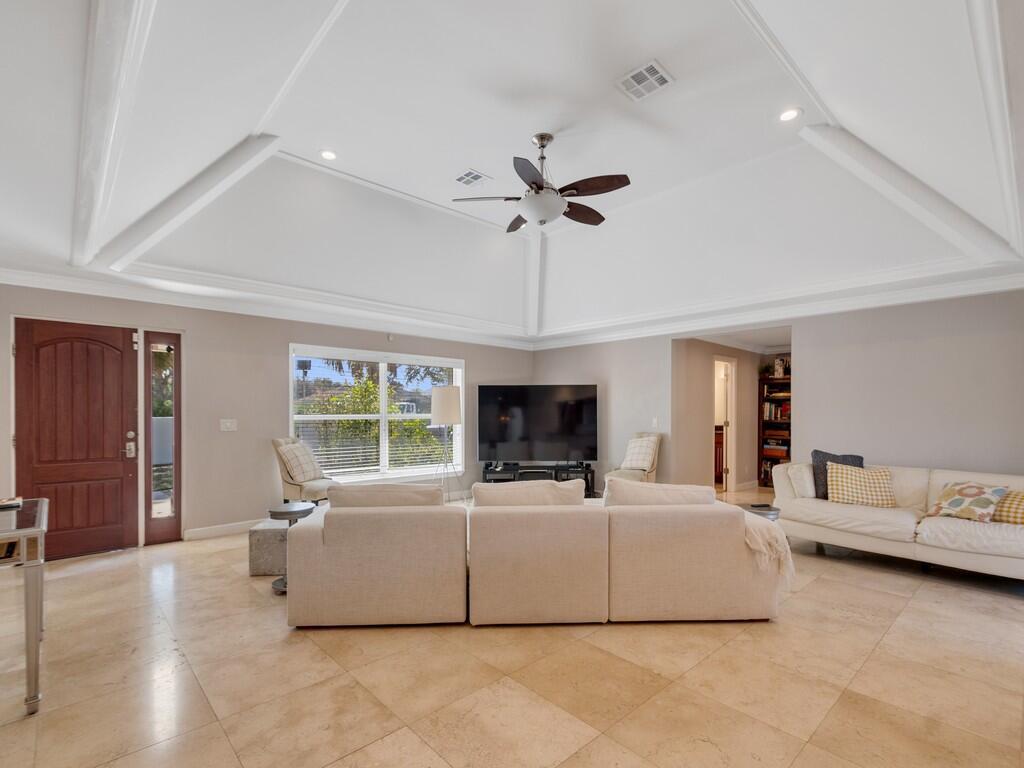 A living room with a vaulted ceiling, tile floors, a sectional sofa, and a television — 527 E Causeway Boulevard, Vero Beach FL 32963, VERO BEACH, FL