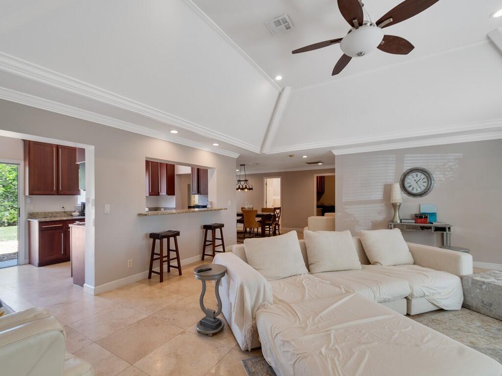 A living room with a vaulted ceiling, white sectional sofa, and an open kitchen pass-through — 527 E Causeway Boulevard, Vero Beach FL 32963, VERO BEACH, FL
