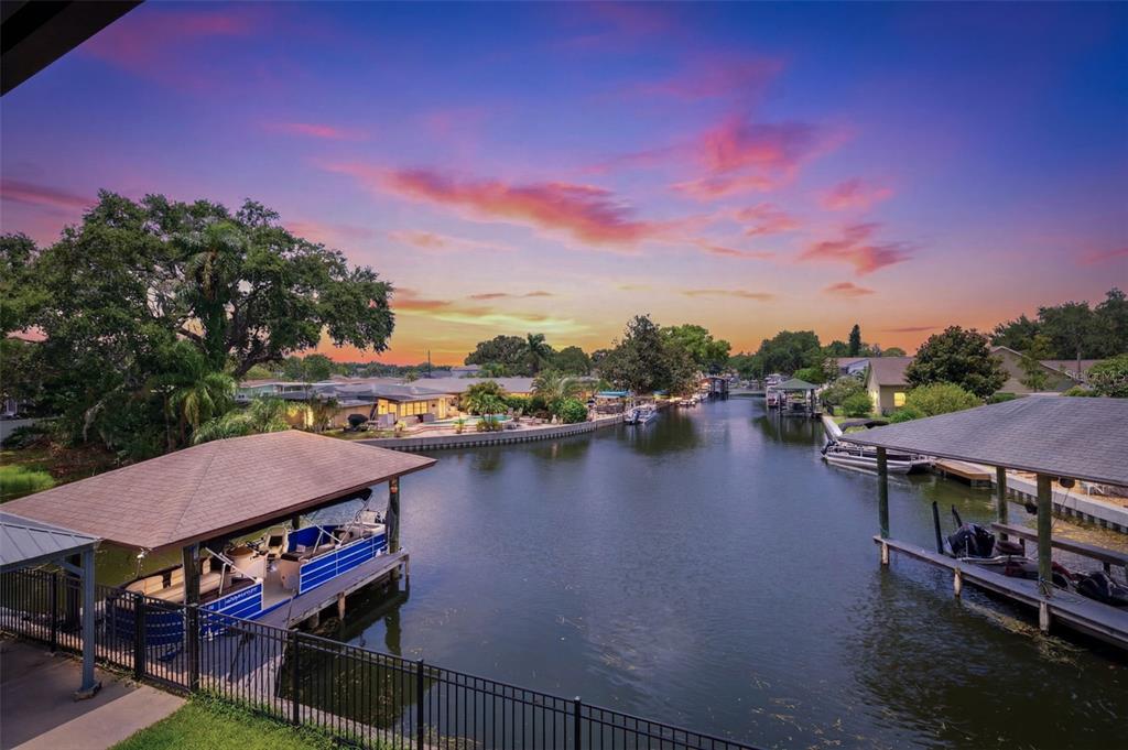 An elevated view of a canal at sunset with boat docks and residential houses — 176 MAPLE AVENUE, PALM HARBOR, FL