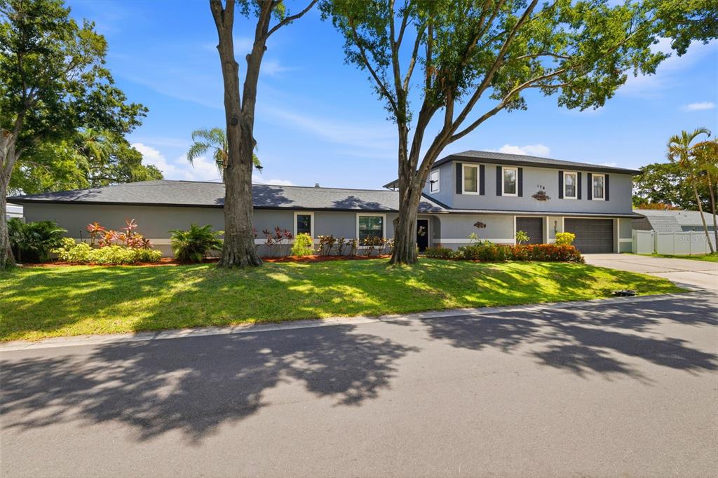 A two-story gray house with a large lawn, mature trees, and an attached garage — 176 MAPLE AVENUE, PALM HARBOR, FL