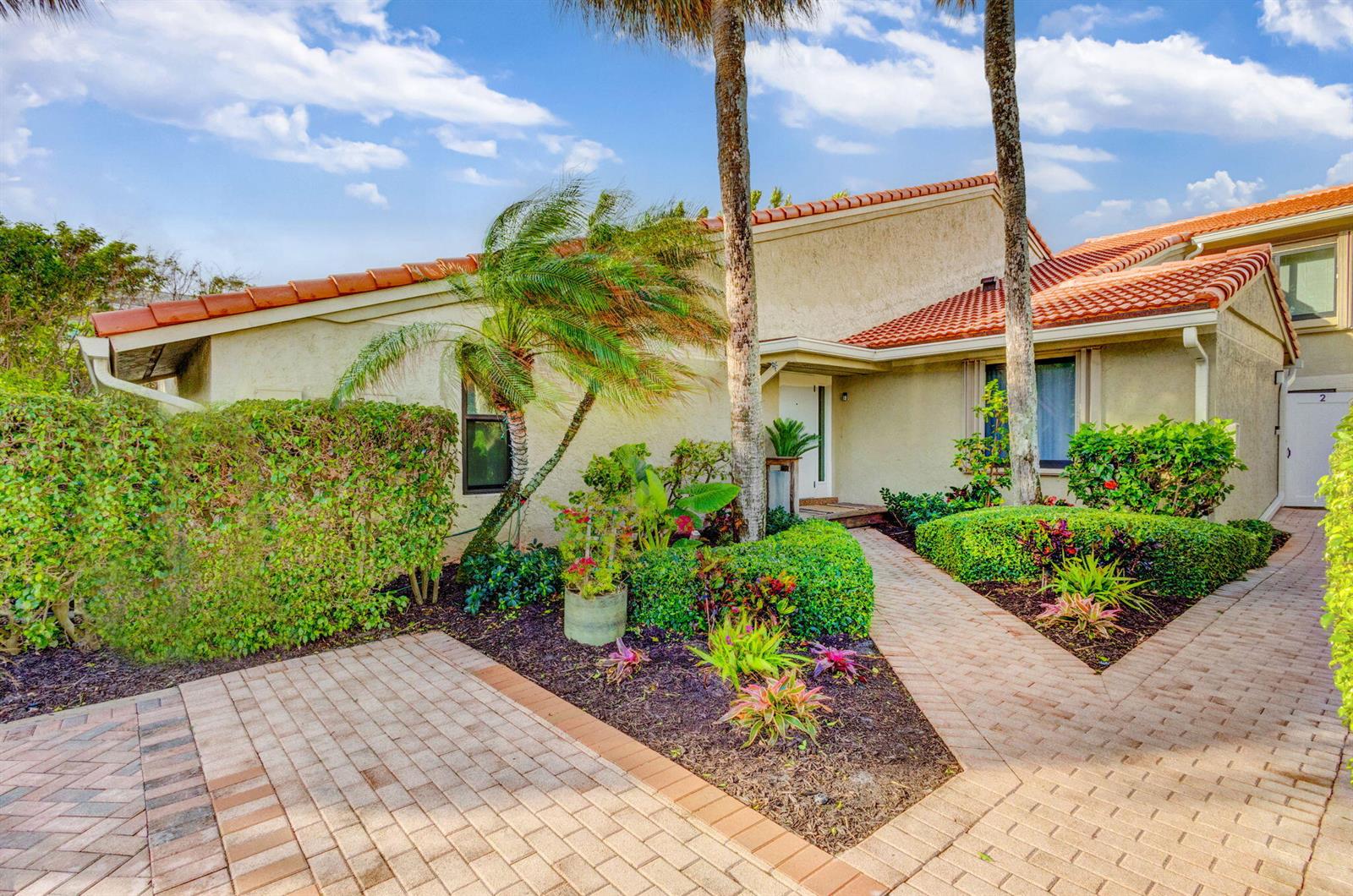 A tan house with a red tile roof features a brick walkway and landscaped garden — 6550 N Ocean Boulevard # 1, Ocean Ridge FL 33435, OCEAN RIDGE, FL
