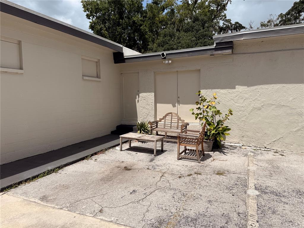 An outdoor patio area features a wooden bench, a chair, and a table on concrete — 209 PONCE DE LEON BOULEVARD, BROOKSVILLE, FL