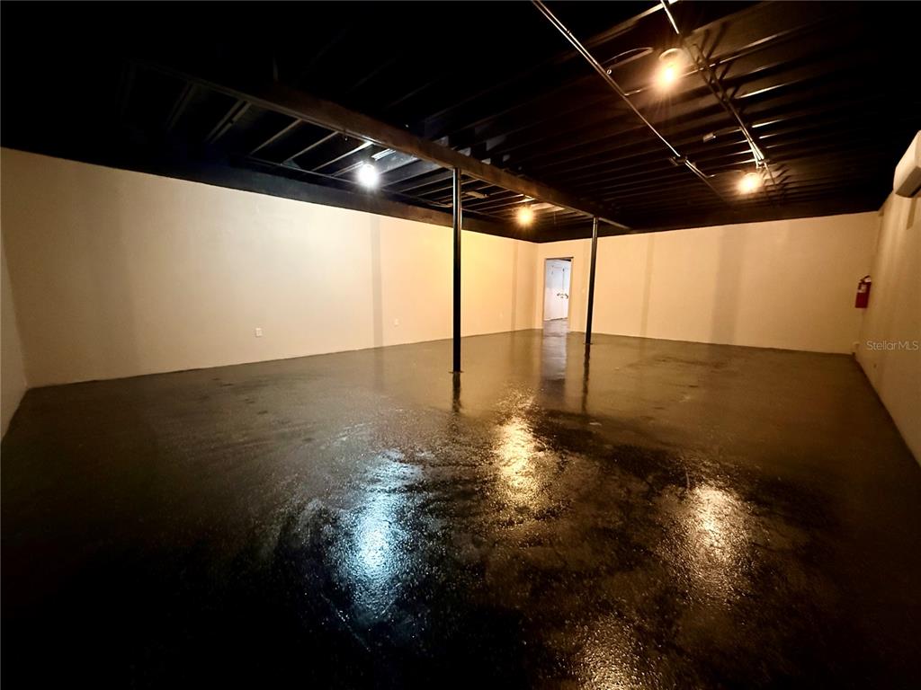An unfinished basement with a black ceiling, support columns, and a glossy dark floor — 209 PONCE DE LEON BOULEVARD, BROOKSVILLE, FL