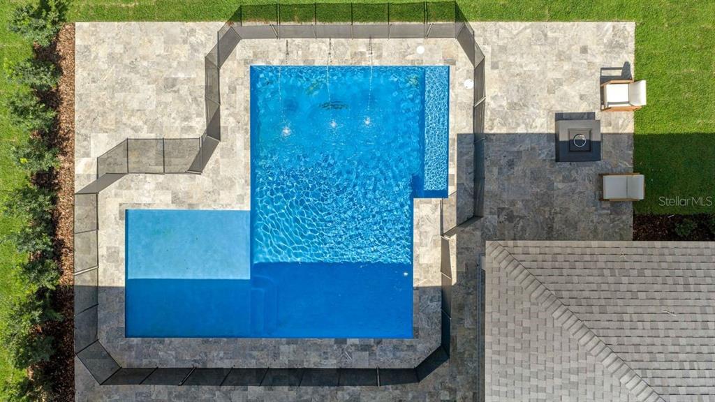 An aerial view shows a rectangular swimming pool with a sun shelf and water features — 1680 SE 20TH AVENUE, OCALA, FL