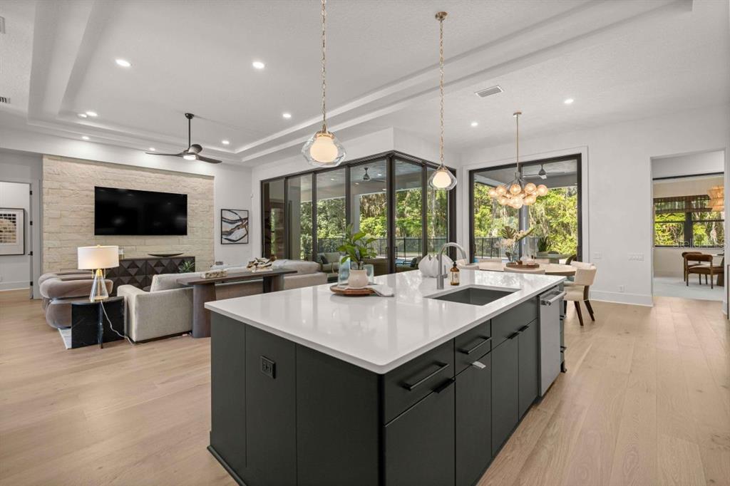 A modern open-concept kitchen with a dark island and white countertops overlooking a living area — 1680 SE 20TH AVENUE, OCALA, FL