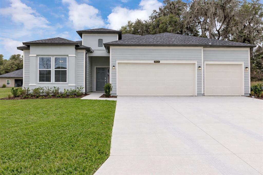 A light gray single-story house features a three-car garage and a front entrance — 19426 SW 79TH STREET, DUNNELLON, FL