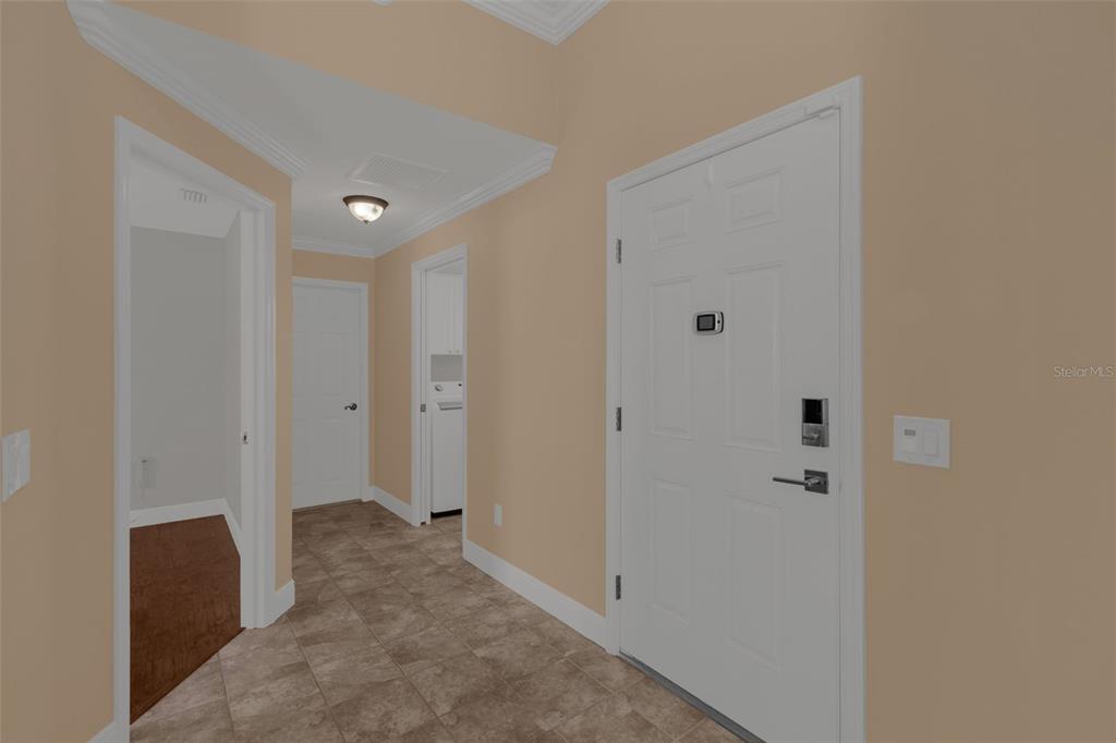 An entryway features tan walls, tile flooring, a white front door, and multiple interior doors — 3369 OVERLAND TERRACE, THE VILLAGES, FL