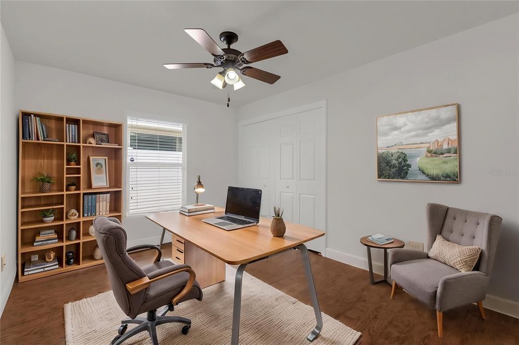 A home office features a wooden desk, bookshelf, gray armchair, and a ceiling fan — 3369 OVERLAND TERRACE, THE VILLAGES, FL