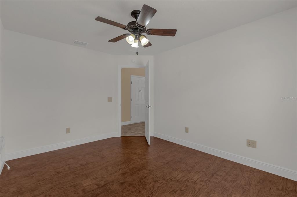An empty room features wood-look flooring, white walls, and a ceiling fan with lights — 3369 OVERLAND TERRACE, THE VILLAGES, FL