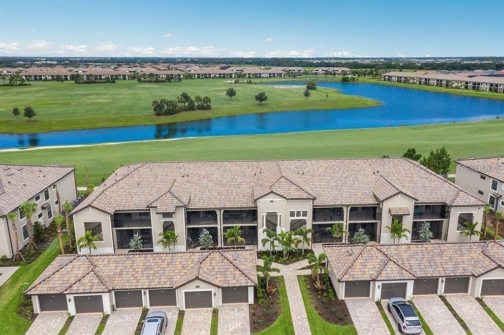 An aerial view of a multi-unit residential building overlooking a golf course and lake — 5674 PALMER CIRCLE UNIT 206, BRADENTON, FL