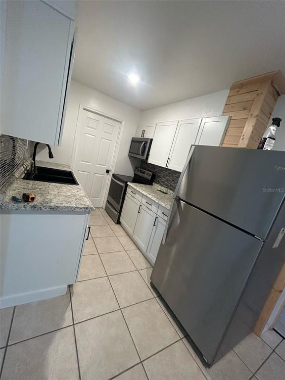 A kitchen features white cabinets, granite countertops, stainless steel appliances, and light-colored tile flooring — 809 PLUMOSA AVENUE, FRUITLAND PARK, FL