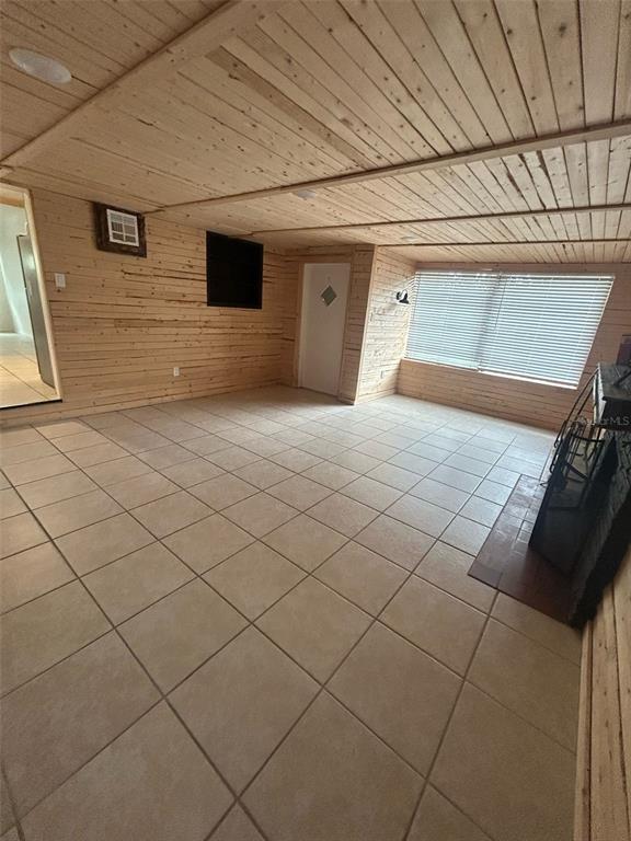 A room with light wood-paneled walls and ceiling, tiled flooring, and a stone fireplace — 809 PLUMOSA AVENUE, FRUITLAND PARK, FL