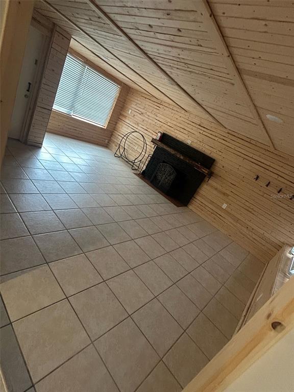 A room with wood-paneled walls and ceiling, tile flooring, and a black fireplace — 809 PLUMOSA AVENUE, FRUITLAND PARK, FL