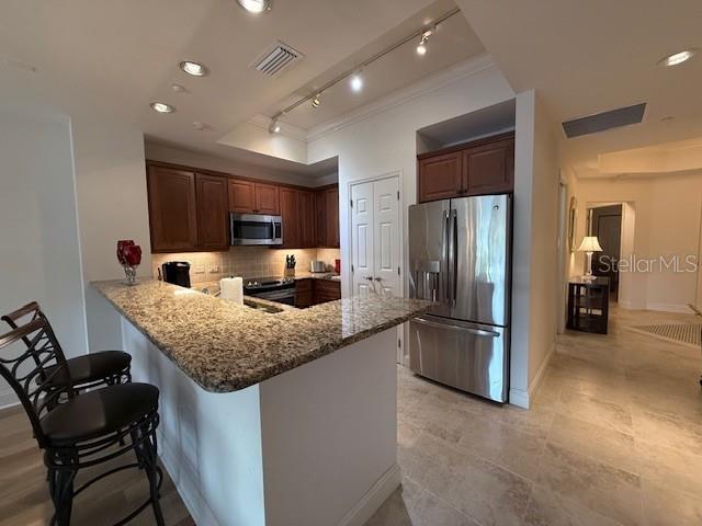 A kitchen features granite countertops, dark wood cabinets, stainless steel appliances, and tile flooring — 7710 LAKE VISTA COURT UNIT 302, LAKEWOOD RANCH, FL