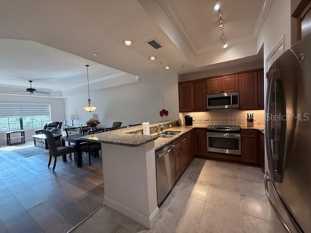 A kitchen with wood cabinets and granite countertops opens to a dining and living area — 7710 LAKE VISTA COURT UNIT 302, LAKEWOOD RANCH, FL