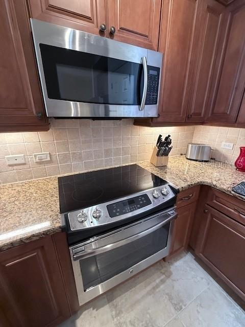 A kitchen features dark wood cabinets, a stainless steel microwave, and a glass-top electric range — 7710 LAKE VISTA COURT UNIT 302, LAKEWOOD RANCH, FL