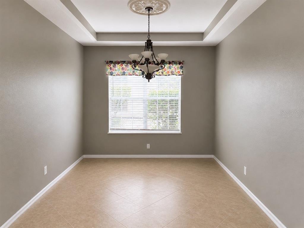 An empty dining room features a tray ceiling, a chandelier, and a window with blinds — 10103 DEERCLIFF DRIVE, TAMPA, FL