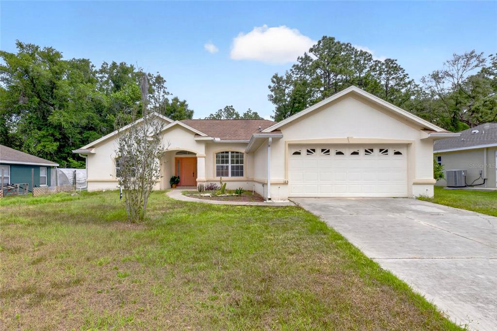 A single-story house with a white stucco exterior, a two-car garage, and a front lawn — 123 W CAMINO LANE, CITRUS SPRINGS, FL