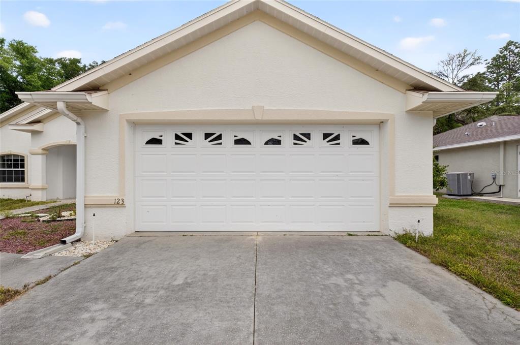 The exterior of a house features a white garage door with windows and a driveway — 123 W CAMINO LANE, CITRUS SPRINGS, FL