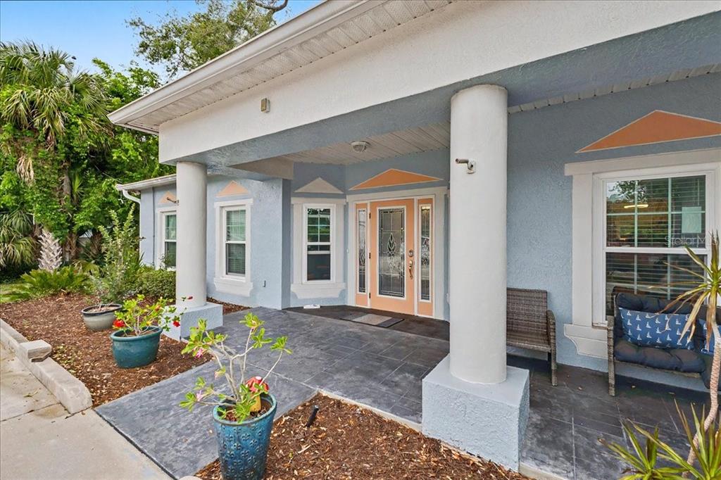 A light blue house exterior features a covered porch with white columns and a front door — 1830 ORANGE TREE DRIVE, EDGEWATER, FL