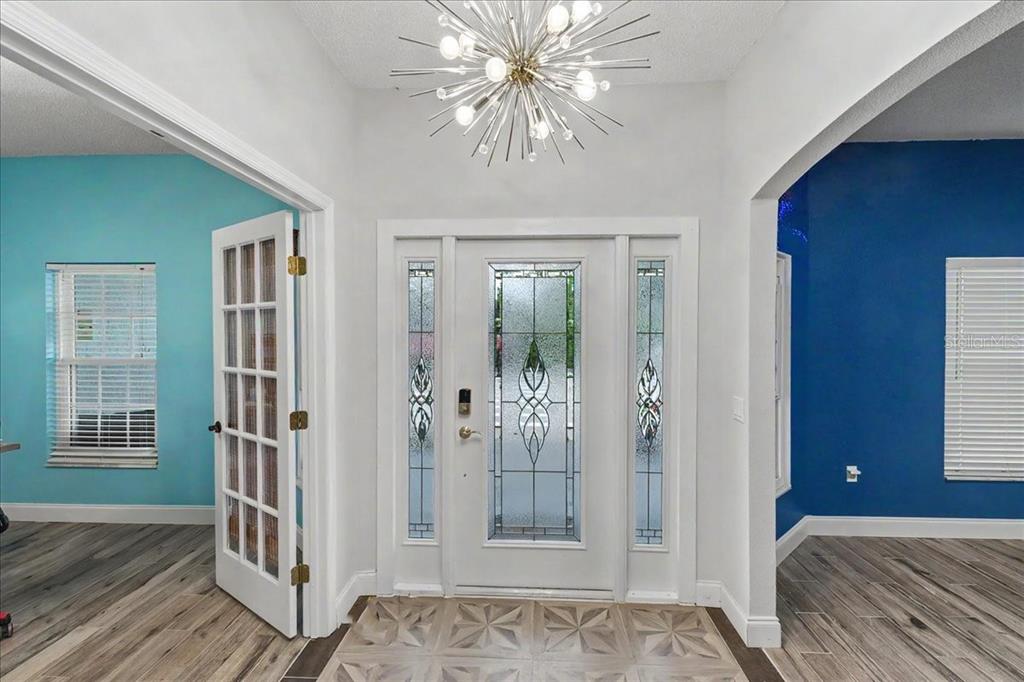An entryway features a white front door with glass panels, a starburst chandelier, and tile — 1830 ORANGE TREE DRIVE, EDGEWATER, FL