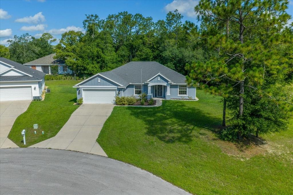 An aerial view of a single-story blue house with a two-car garage and lawn — 9928 SW 194TH COURT, DUNNELLON, FL