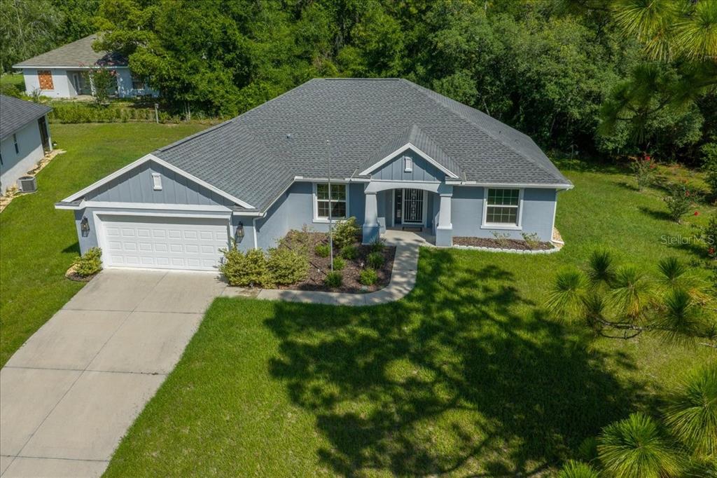 An aerial view of a blue single-story house with a gray roof and concrete driveway — 9928 SW 194TH COURT, DUNNELLON, FL