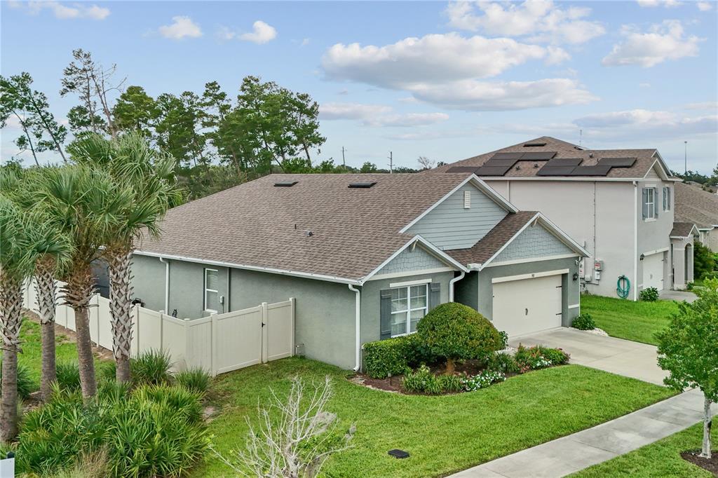 An exterior view of a single-story suburban house with a garage and solar panels — 907 GUADALUPE, ORANGE CITY, FL