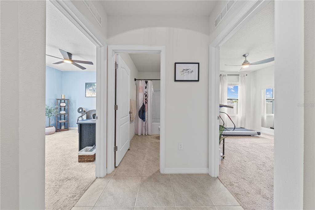 A hallway with tile flooring leads to a central bathroom flanked by two carpeted rooms — 907 GUADALUPE, ORANGE CITY, FL