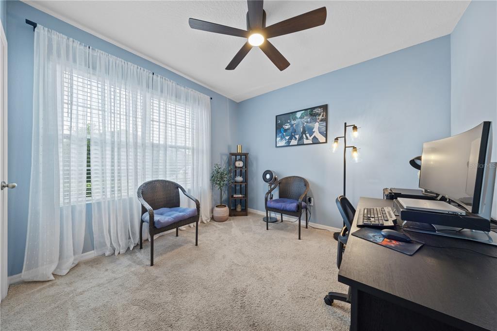 A home office with light blue walls, a desk, two wicker chairs, and a ceiling fan — 907 GUADALUPE, ORANGE CITY, FL