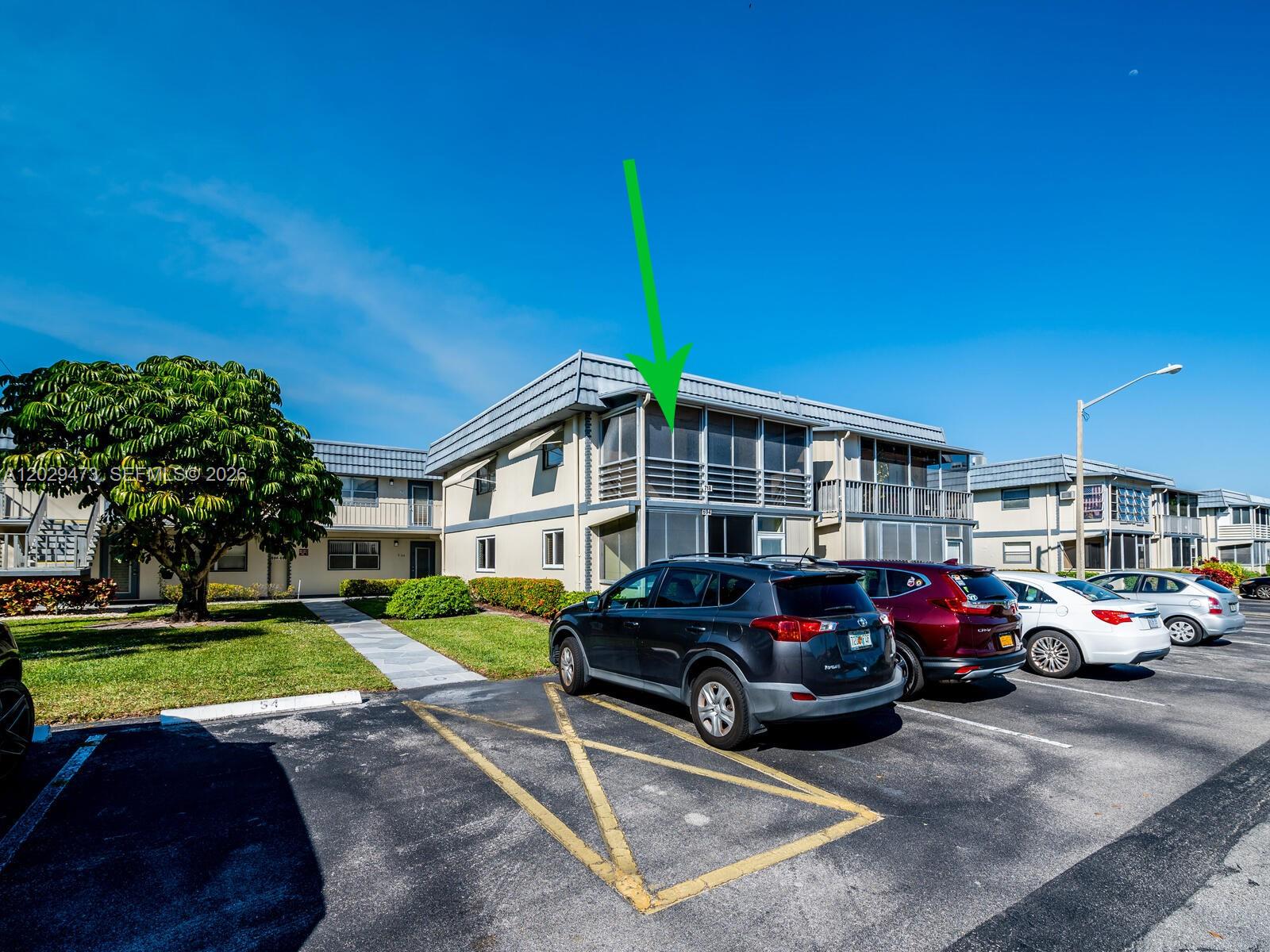 An exterior view of a two-story apartment building with a green arrow pointing to a balcony — 718 Brittany O # 718, Delray Beach FL 33446, DELRAY BEACH, FL