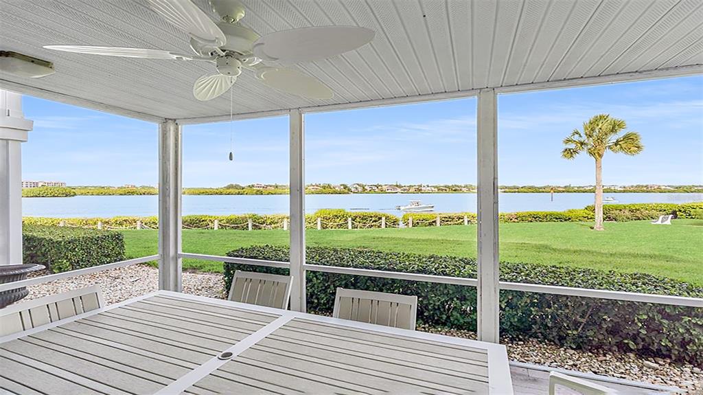 A screened-in porch features a ceiling fan, a dining table, and a view of water — 1360 SIESTA BAYSIDE DRIVE UNIT 1360-D, SARASOTA, FL