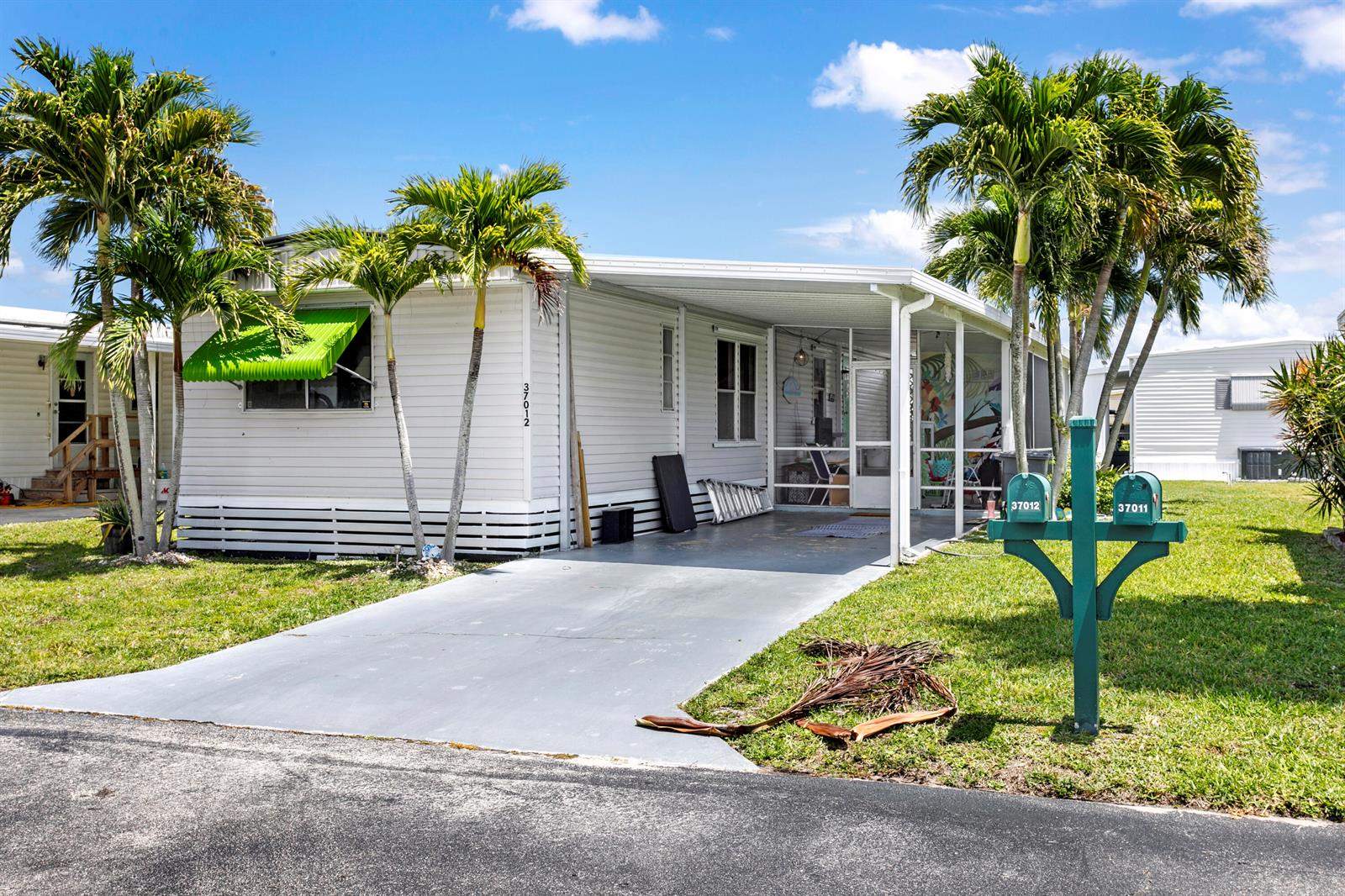 A white mobile home features a carport, a screened-in porch, and two palm trees — 37012 Exuma Bay, Boynton Beach FL 33436, BOYNTON BEACH, FL