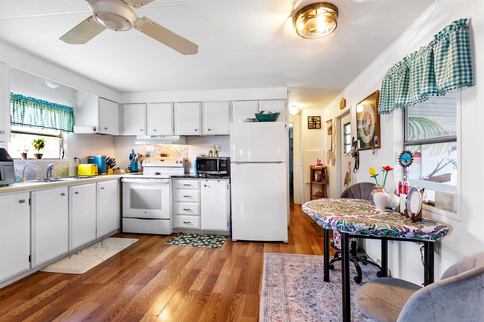 A kitchen with white cabinets, white appliances, wood flooring, and a small dining table — 37012 Exuma Bay, Boynton Beach FL 33436, BOYNTON BEACH, FL