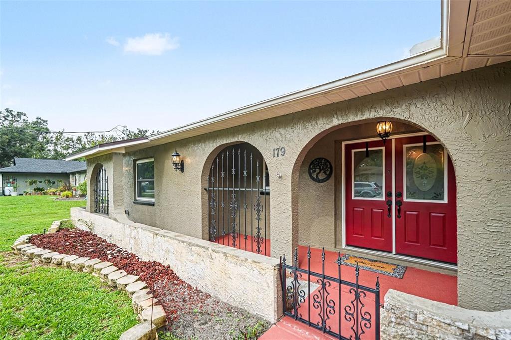 A house exterior features a red double front door, arched entryways, and a stone-walled porch — 179 HAGUE COURT UNIT 5, SPRING HILL, FL