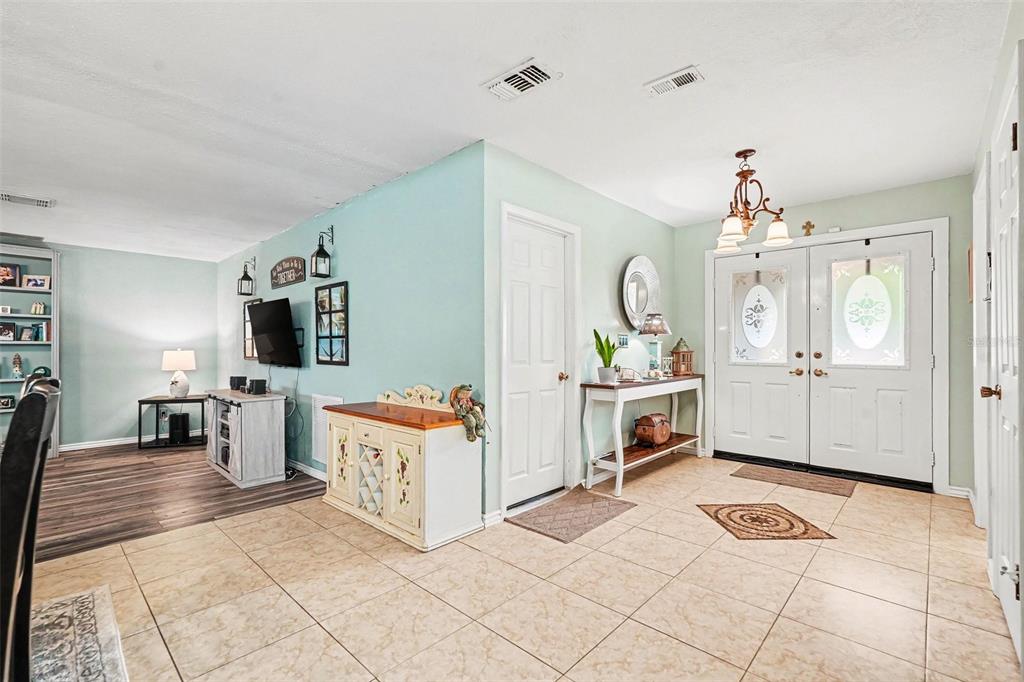 An entryway with tile flooring leads into a living area with wood-look floors and light-blue walls — 179 HAGUE COURT UNIT 5, SPRING HILL, FL