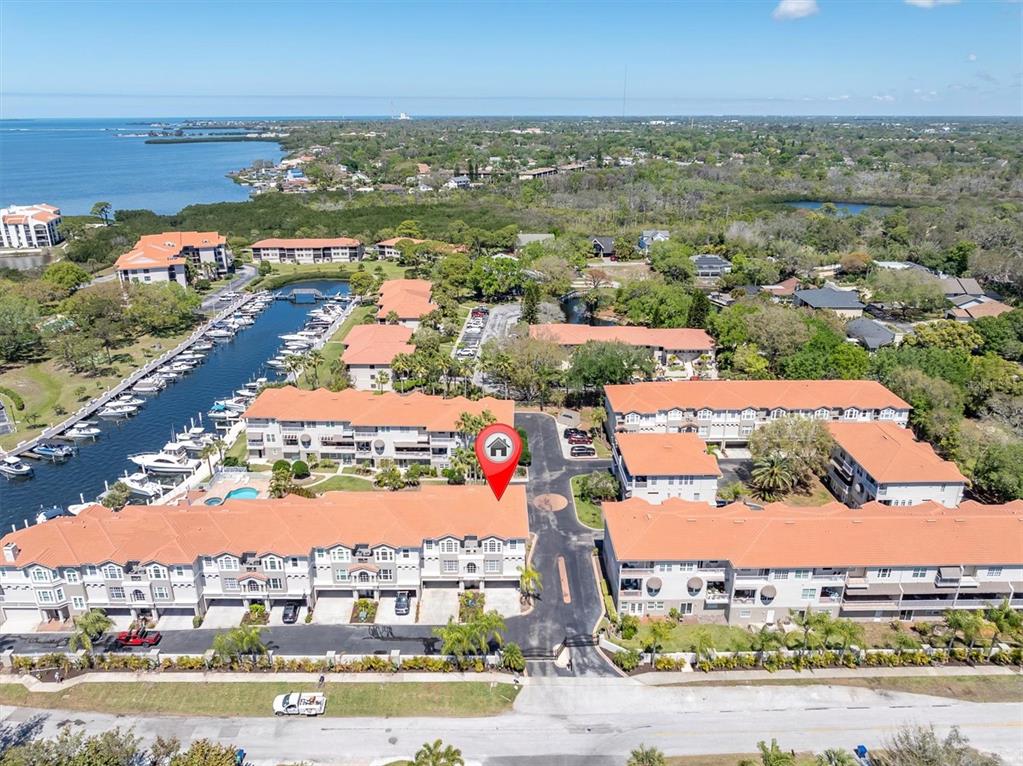 An aerial view shows a multi-story residential complex with orange roofs near a marina — 1501 WHARFSIDE DRIVE, TARPON SPRINGS, FL