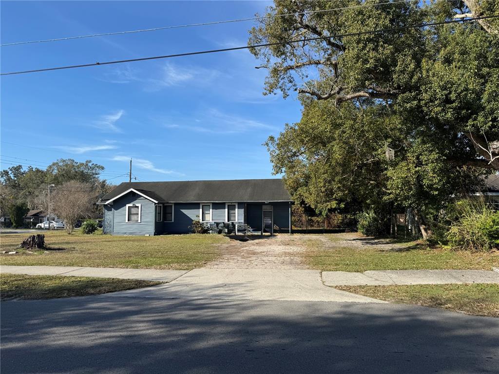 A single-story blue house with a gravel driveway sits on a grassy lot — 1049 PLATEAU AVENUE, LAKELAND, FL
