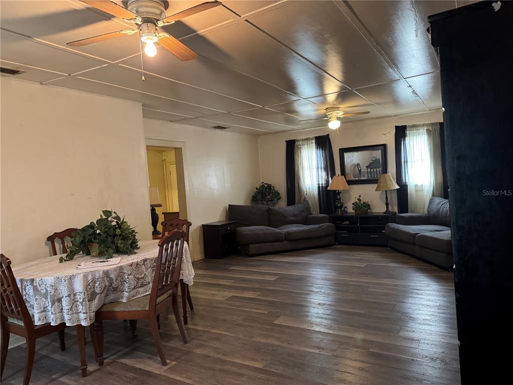 A living and dining room with wood-look flooring, two ceiling fans, and dark furniture — 1049 PLATEAU AVENUE, LAKELAND, FL