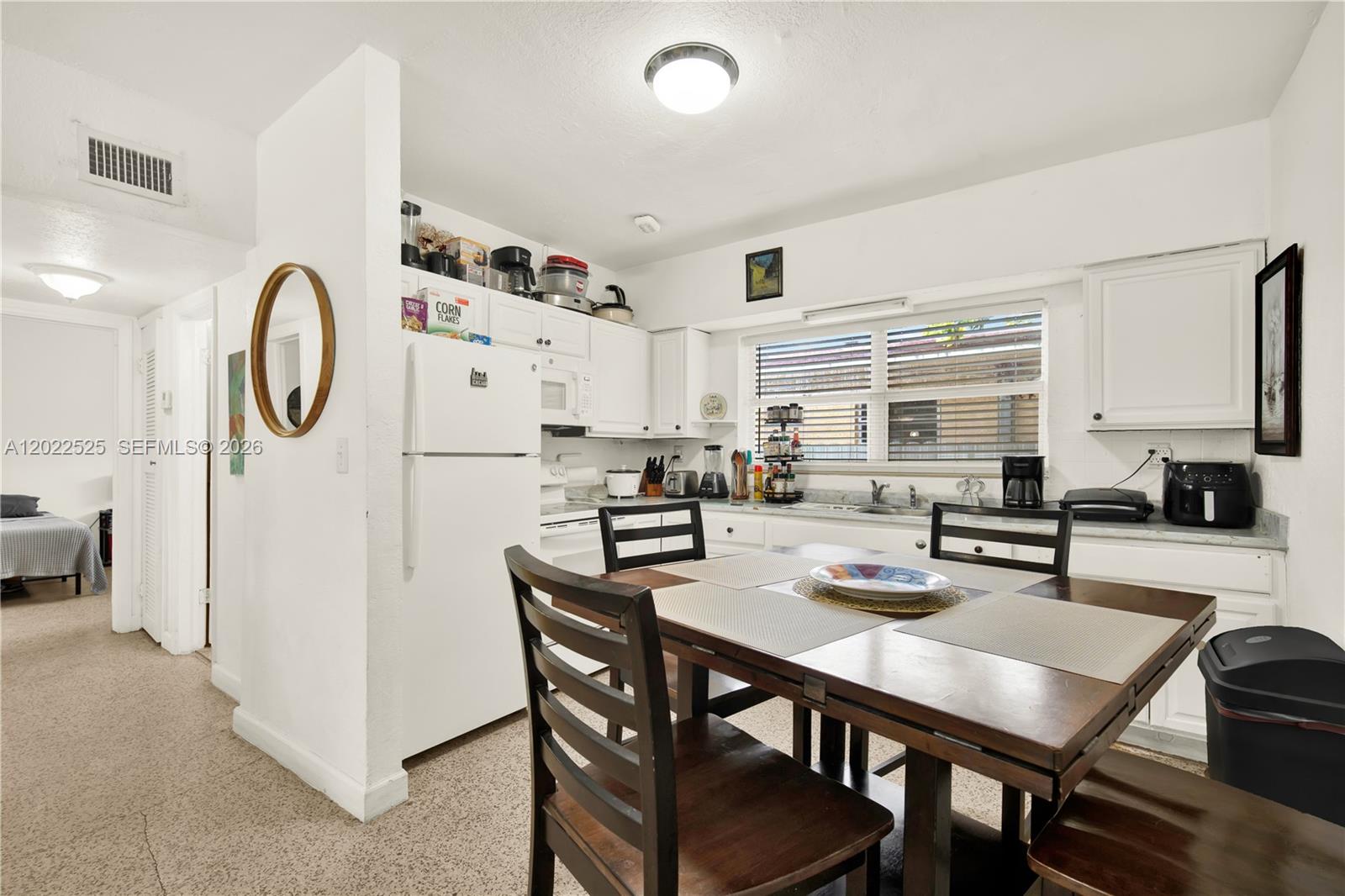 A kitchen with white cabinets, a dining table, and a white refrigerator — 1236 NE 109th St # 2, Miami FL 33161, MIAMI, FL