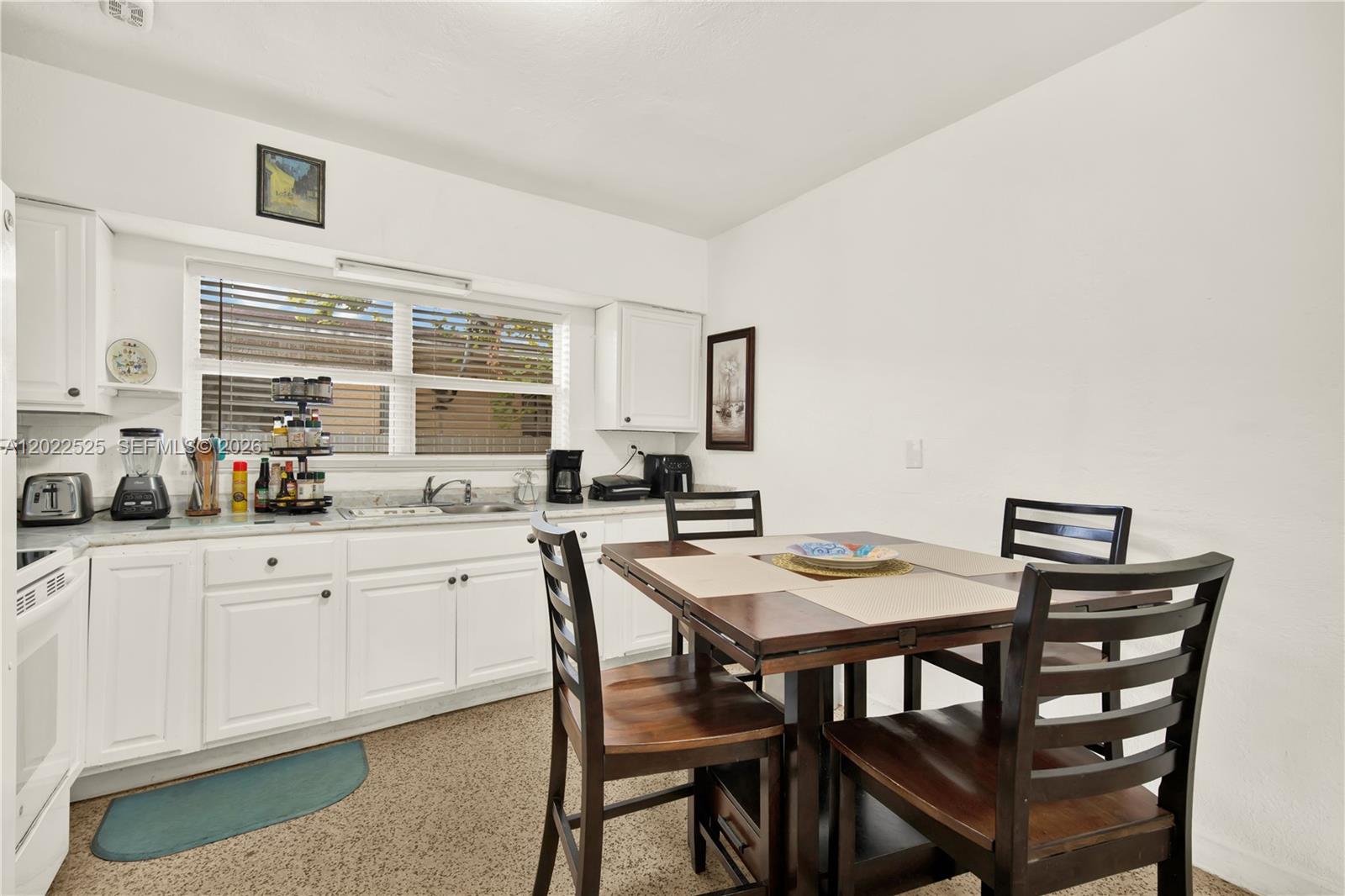 A kitchen features white cabinets, a dining table with four chairs, and a window — 1236 NE 109th St # 2, Miami FL 33161, MIAMI, FL
